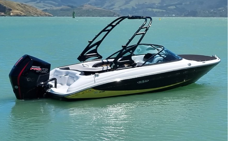 Black and white boat on a calm body of water with mountains in the background